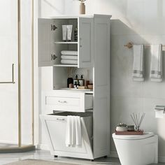 a white toilet sitting in a bathroom next to a cabinet with towels on top of it