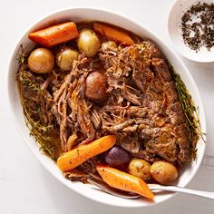 a white bowl filled with meat, potatoes and carrots