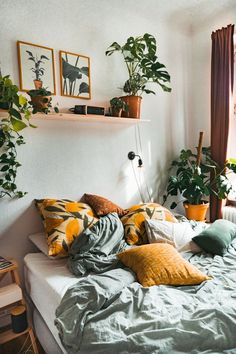 a bed with lots of pillows and plants on it