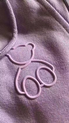 a teddy bear embroidered on the back of a purple shirt with an o - ring