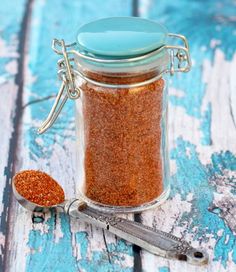 a glass jar filled with red glitter next to a pair of scissors on top of a wooden table