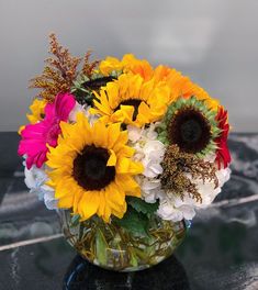 a vase filled with lots of different colored flowers on top of a black countertop