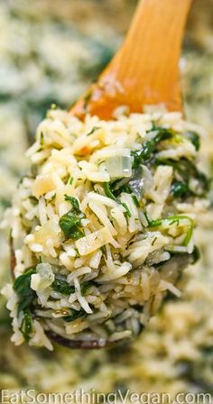 a wooden spoon filled with rice and spinach