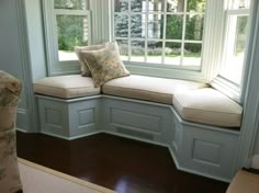 a corner window seat with pillows on it