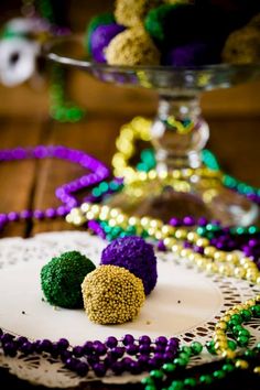 mardi gras decorations are displayed on a doily in front of a cake