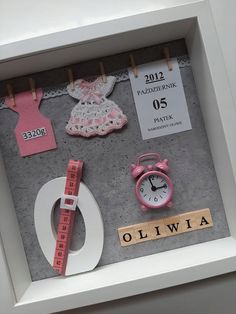 a display case with clothes, clock and name tag on the wall next to it