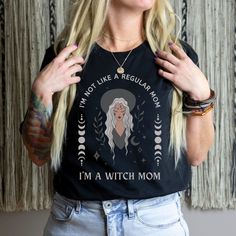 This witchy goth tee is perfect for any mom who is not like a regular mom, she's a witch mom! Makes a perfect gift for any spooky, alternative, cool mom. Bella+Canvas tees are UNISEX SIZES and run longer and less fitted than a classic women's cut tee, but smaller and more fitted than a men's traditional cut. Wear knotted, tucked, or size up for that trendy oversized look! Ringspun cotton is soft and lightweight with the perfect amount of stretch. We recommend laying a favorite tee flat and measu Witchy Cotton Tops With Letter Print, Cotton T-shirt For Alternative Fashion In Fall, Mother's Day Black T-shirt With Funny Print, Mom Goth, Witch Mom, Aesthetic Tshirt, Anti Christianity, Witchy Aesthetic, Anti Religion