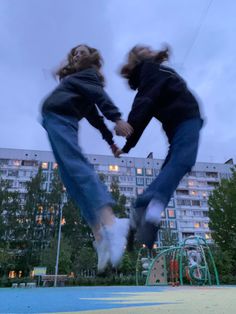 two people jumping in the air with their hands together