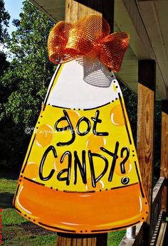 an orange and white sign that says got candy? on the side of a wooden post