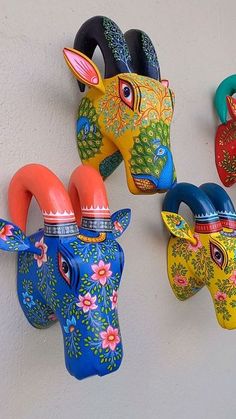 four brightly colored animal heads are hanging on the wall, each painted with different colors