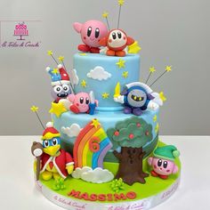 a three tiered cake decorated with cartoon characters and rainbows on the bottom layer