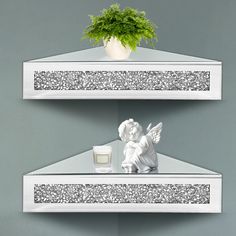 two white shelves with angel figurines on them and a plant in the corner