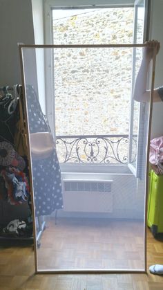 the reflection of a window in a mirror with clothes and shoes on the floor next to it