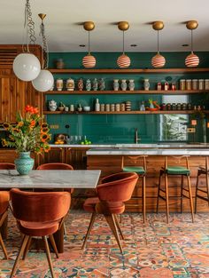 a dining room table surrounded by chairs and hanging lights