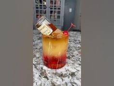 a glass filled with liquid sitting on top of a counter next to a red and yellow drink