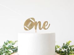 a cake topper that says one with a football on it