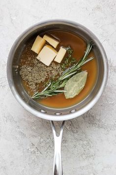 a pot filled with soup and herbs on top of a table