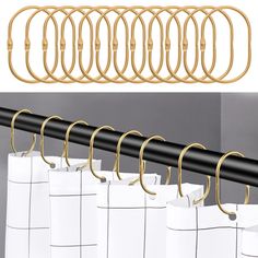 a set of six gold metal curtain hooks on the side of a white shower curtain