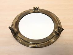 an old brass porthole mirror on a wooden table