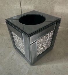 a black trash can sitting on top of a floor next to a tile countertop