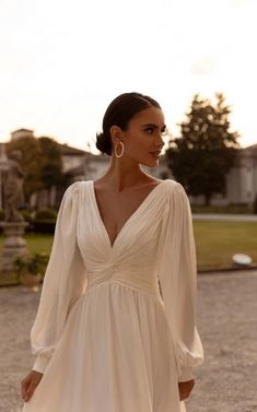 a woman in a white dress is standing outside