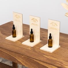 three small bottles are sitting on the table with two stands holding each one's own essential oils