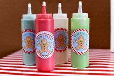 three baby bottles sitting on top of a red and white striped tablecloth with one bottle in the shape of a teddy bear