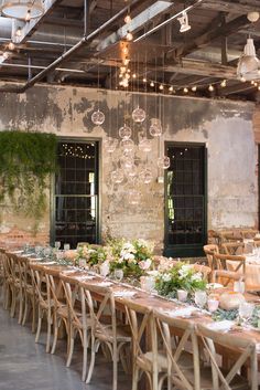 a long table is set with flowers and greenery in front of an old building