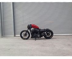 a red and black motorcycle parked in front of a garage door