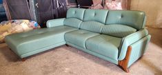 a blue leather couch sitting on top of a floor next to a wooden frame chair