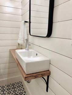 a white sink sitting under a bathroom mirror next to a black and white tiled floor