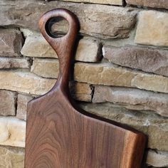 a wooden cutting board sitting next to a brick wall