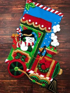 a christmas stocking with a train and snowman in it on a wooden surface