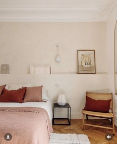 a bed room with a neatly made bed next to a mirror and two wooden chairs