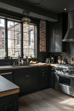 a kitchen with black cabinets and stainless steel appliances in the center, along with wooden flooring