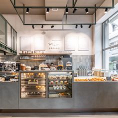 the inside of a bakery with lots of food and drinks on display in front of large windows