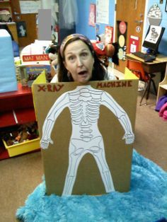 a woman holding up a cardboard cutout of a human body in a classroom setting