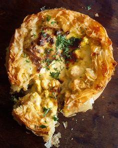 an omelet with meat and vegetables is on a wooden table