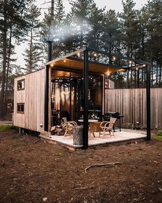 a small wooden cabin in the woods with lights on it's roof and patio area