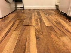 a wood floor that has been sanded and is next to a white refrigerator freezer