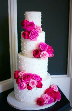 a three tiered white cake with pink flowers on top