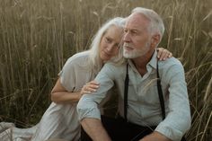 an older man and woman sitting in tall grass