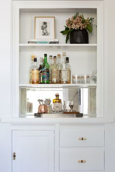 a white shelf filled with lots of bottles and glasses