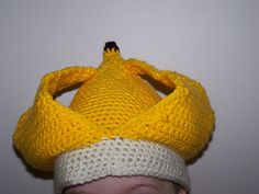 a young child wearing a knitted yellow and white crochet hat with a crown on top