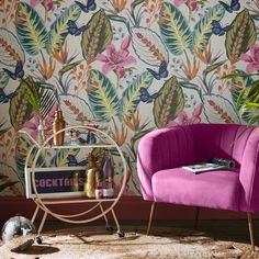 a pink chair sitting in front of a colorful wallpaper