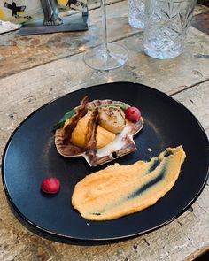 a plate with food on it sitting on top of a wooden table next to wine glasses