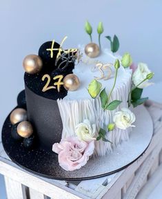 a black and white cake with gold numbers on it sitting on top of a table