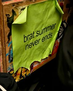 a green paper sign that says brat summer never ends