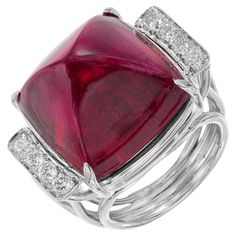 1950's Beautiful sugar loaf cut red Tourmaline Rubellite and diamond cocktail ring. This stunning rich red cabochon tourmaline is 27.49cts and is mounted in a platinum handmade wire gallery and shank. The stone is accented with 4 round cut diamonds on each side of the stone. Certified by the GIA as a genuine Tourmaline. Heat treatment cannot be determined. This stone is both deep and bright in color depending on the lighting. Simply spectacular. 1 cushion cabochon purplish red Tourmaline, approx Gia Certificate, Red Tourmaline, Diamond Cocktail Rings, Handmade Wire, Cocktail Ring, Round Cut Diamond, Cocktail Rings, Round Cut, Tourmaline