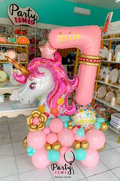 an inflatable unicorn is sitting on top of some pink and blue balloons at a store